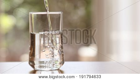 Close up pouring purified fresh drink water from the bottle on table in living room