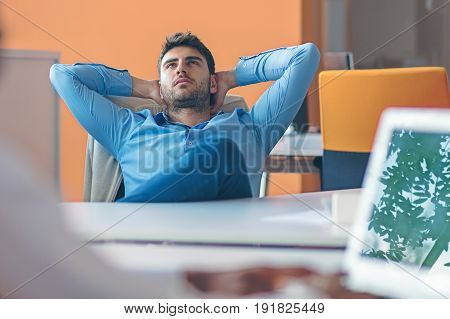 caucasian business person sitting in office thinking daydreaming hands behind head