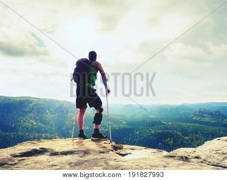 Man With A Crutches In Nature. Tourist With Broken Leg On Crutches. Traveler With Hurt Leg In Bandag