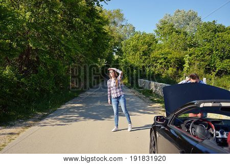 Young couple on the road has problems with their car.