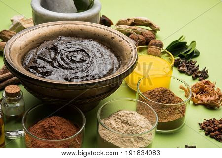 Flat lay of a bowl of Chyawanprash or chyavanprash and all its ingredients on a green background.
