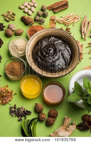 Flat lay of a bowl of Chyawanprash or chyavanprash and all its ingredients on a green background.