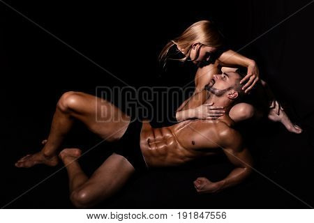 couple in love of man with muscular wet body and strong athletic torso with sexy blonde girl in underwear pants on black background love relations