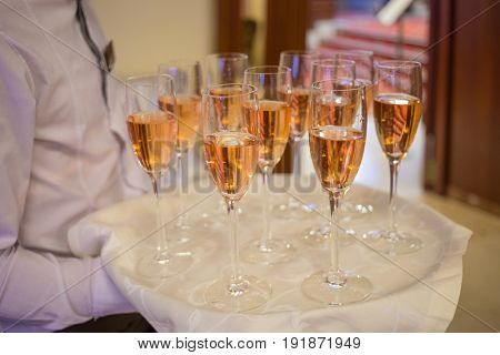 Waiter in shirt holds tray with wine and napkin during event, noface
