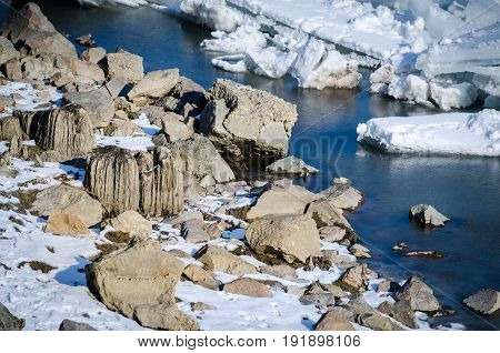 Rocks in frozen Danube river. Winter image of rocks covered by snow and ice in the water. Novi Sad, Serbia.