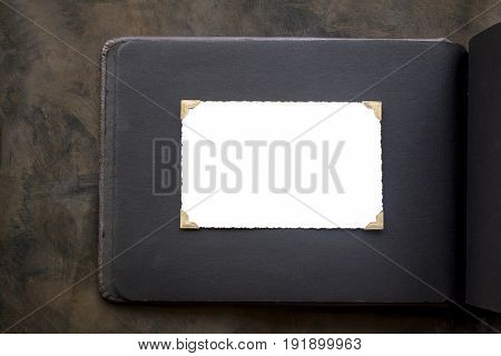 Photo frame - real old photo with white blank space for copy photo with gold coloured photo holder corners onto black vintage album paper page - top view background with space for text