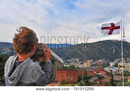 Little traveller waithing in binoculars over the skyline of Tbilisi Georgia