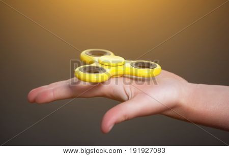 Little girl is playing a yellow spinner in her hand outdoors.