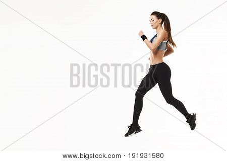 Young beautiful athletic girl in sportswear training running over white background. Copy space.