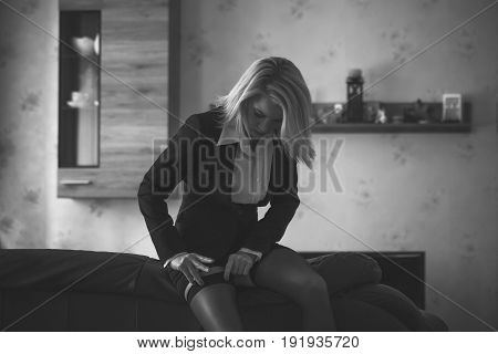 Sexy blonde businesswoman pulling up stockings under skirt before workday black and white