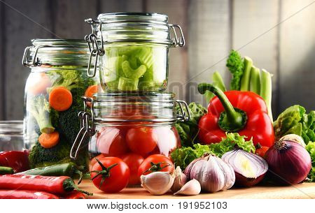 Jars With Marinated Food And Raw Vegetables On Cutting Board