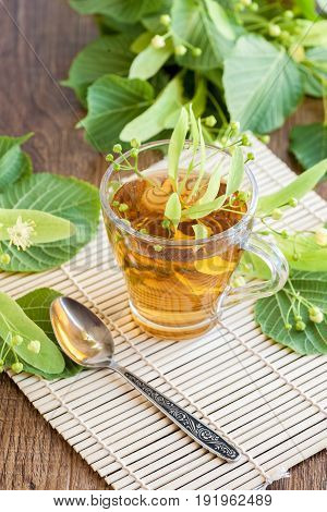 Lime flower tea in glass cup with linden flowers. midicinal remedy.