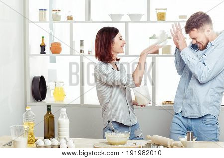 Funny Couple in love cooking dough and having fun with flour in the kitchen