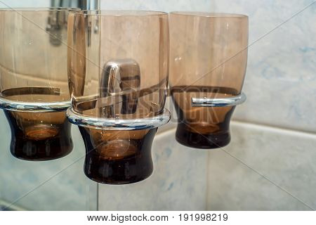 Close up set of empty glasses hanging on tap in bathroom