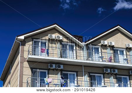 The Upper Part Of The Facade Of A Two-story House Of Beige Color Against A Blue Sky.