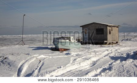 hut and boat of the fisherman at the edge of the river during the winter
