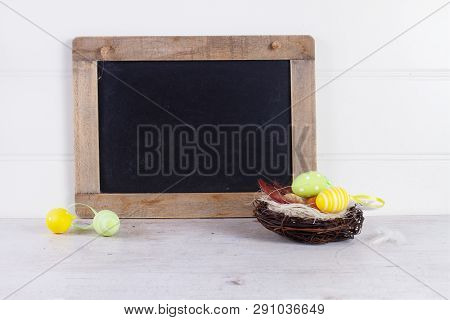 Easter Scene With Colored Eggs In Nest, Copy Space On Blackbord
