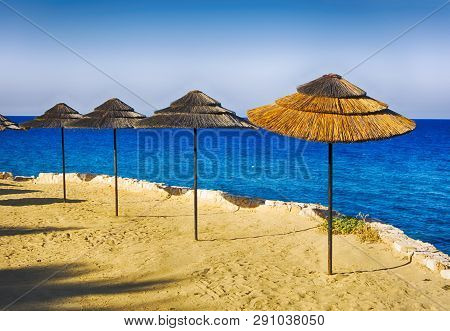 Strawy beach umbrellas on the sea beach.