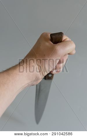 Mans Hand With A Knife On Gray Background. Concept Of Violence. Hand Of A Gangster With A Knife. Cop