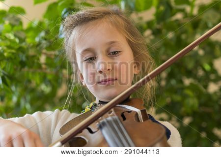 Close Up Of A Child Playing Violin On Green Background. Portrait Of Girl With String And Playing Vio