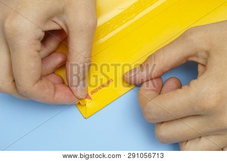 Woman Hands Opening Mail Package With Easy Open Strip.
