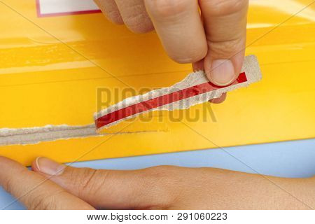 Woman Hands Opening Mail Package With Easy Open Strip. Close-up.