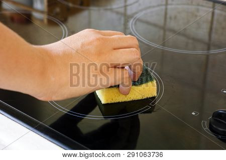 Woman Hand With Yellow Sponge Cleaning Ceramic Hob.