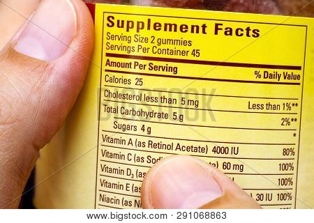 Plastic Jar With Supplement Facts Of Multivitamins In Woman Hands. Close-up.