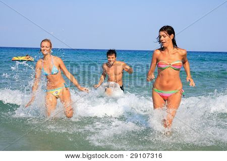 Gruppo di tre amici - uomo e donna - sulla spiaggia avendo un sacco di divertimento in vacanza in Grecia