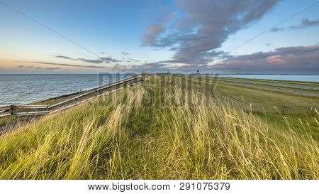 Afsluitdijk Dutch Dike With Fence Motorway And Cycling Track During  Sunset With Clouded Sky