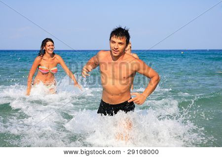 Gruppo di tre amici - uomo e donna - sulla spiaggia avendo un sacco di divertimento in vacanza in Grecia