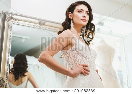 Beautiful bride choosing wedding dress in a wedding salon