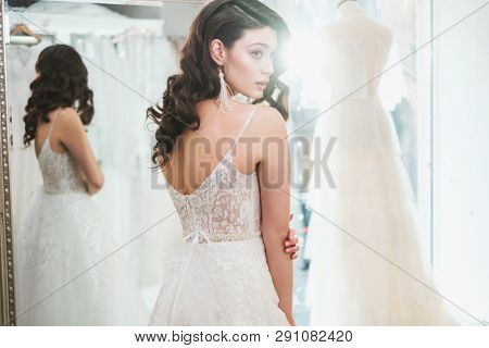 Beautiful bride choosing wedding dress in a wedding salon
