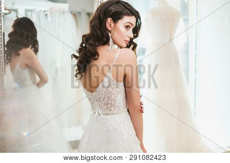 Beautifu bride choosing wedding dress in a wedding salon