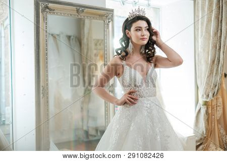 Beautiful bride choosing wedding dress in a wedding salon