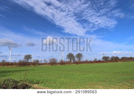 View On Alternative Energy Windmills In A Windpark In Northern Germany In Front Of A Blue Sky