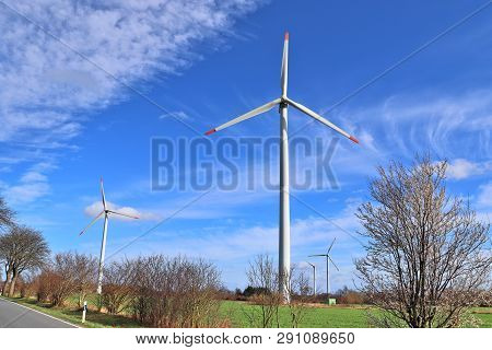View On Alternative Energy Windmills In A Windpark In Northern Germany In Front Of A Blue Sky