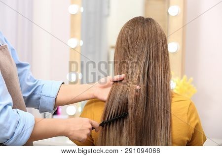 Professional Coiffeuse Combing Client's Hair In Salon