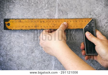 Person Hands Using Setsquare On Gray Wall. Close-up.