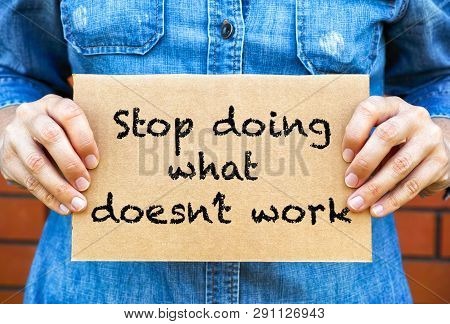 Woman Hands Holding Piece Of Cardboard With Phrase Stop Doing What Doesnt Work Against Brick Wall Ba