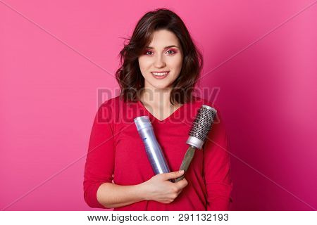 Image Of Female Hairdresser Holds Comb And Hairspay, Wears Red Sweater, Ready To Make Hairstyle Her 