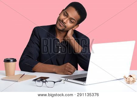 Handsome African American Man Sitting At Desk, Wearing Classic Jacket, Looking Very Tired, Putting H