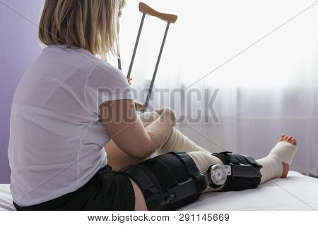 Female Leg After Knee Surgery In Bandages And Orthosis, Close-up