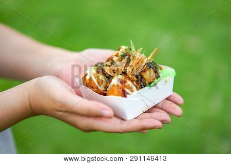 Four Takoyaki, Local Japanese Octopus Meat Ball In The Hand With Blur Grean Background, Ready To Eat