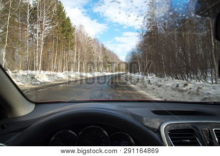 View Of The Road Through The Windshield. Snow On The Sidelines. Wet Asphalt Road. Blue Sky With Clou