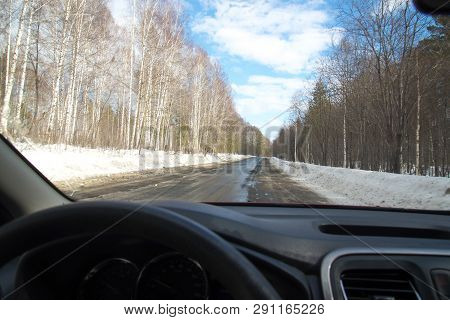 View Of The Road Through The Windshield. Snow On The Sidelines. Wet Asphalt Road. Blue Sky With Clou