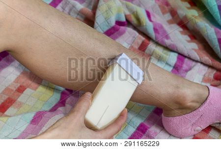 Woman And Her Hairy Leg On A Multi-colored Towel. Girl Carries Out The Procedure Of Depilation By Wa