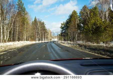 View Of The Road Through The Windshield. Snow On The Sidelines. Wet Asphalt Road. Blue Sky With Clou
