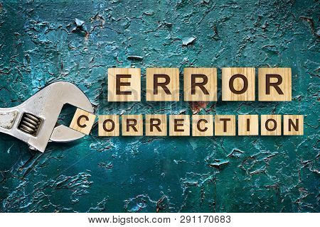 Error Correction, Word Written On Wooden Blocks, Adjustable Wrench On Cracked Blue Background. Error