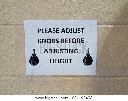 Please Adjust Knobs Before Adjusting Height Sign With Boxing Bag On Wall